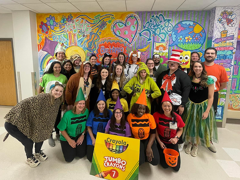 group of residents wearing costumes standing in front of a mural